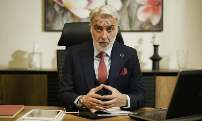 Professional middle-aged businessman sitting confidently at his executive desk in an office setting.