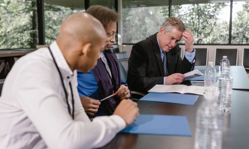 Group of diverse colleagues in a business meeting reviewing documents indoors.