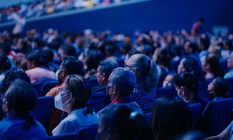 Diverse audience sitting in rows, attending an indoor conference or event.